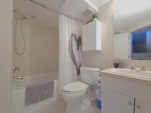 a white bathroom with a toilet and a sink at Entire Home - 2 Separate Units in Calgary +17 photos