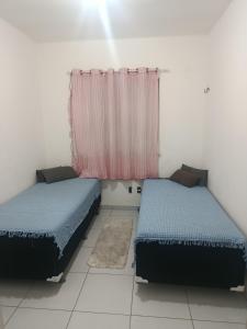 two beds in a room with a window at Rogerio AP Compartilhado in Caucaia +4 photos
