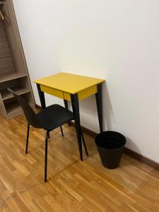 a yellow table and a chair next to a wall at Olympic Lodge in Milan