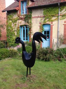 a statue of a black bird in front of a house at La Merlerie in Malicorne