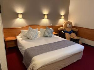 a hotel room with a bed with a teddy bear at Brit Hotel Confort Villeneuve Sur Lot in Bias