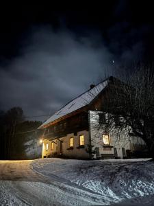 a house with lights on in the snow at night at Steinerhof in Sankt Georgen ob Murau