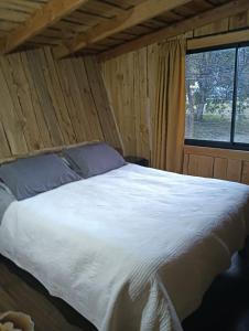 a large bed in a room with a window at Cabañas Río Iculpe in Lago Ranco
