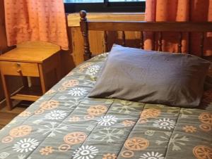 a bed with a pillow on top of it at Cabañas Río Iculpe in Lago Ranco