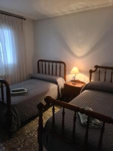 a bedroom with two beds and a table with a lamp at Dos Hermanas in Sahagún