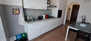 a kitchen with white cabinets and a sink and a table at Via Roma 48 in Arquata Scrivia