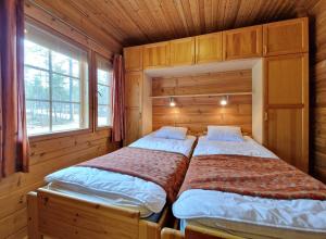 two beds in a wooden room with two windows at Paratiisikuru 2 in Kakslauttanen