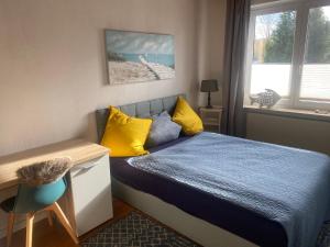 a bedroom with a bed with yellow pillows and a desk at Apartment am Waldrand Nichtraucher gemütlich und ruhig in Itzehoe