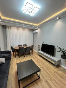 a living room with a couch and a table and a television at Qarb Apartment Dernegul metro in Baku