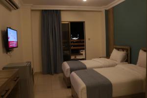 a hotel room with two beds and a television at Mariam Economy Hotel in Aqaba