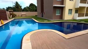 a swimming pool in front of a building with a house at Rogerio AP Compartilhado in Caucaia