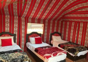 two beds in a room with red walls at Rum Sky Experiences in Wadi Rum
