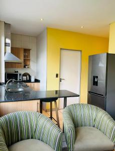 a kitchen with a table and a kitchen with yellow walls at Seven Eleven Apartments - Isibaya House in Johannesburg
