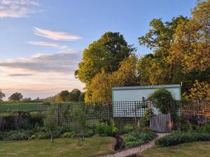 a garden with a white building in the background at The Old Mill Shepherds Hut in Okehampton