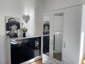 a white cabinet with a mirror and a woman wearing a hat at Kingsbury Service Accommodation in Colindale