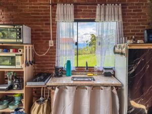 a kitchen with a sink and a window at Chalé Agulhas Negras in Resende +35 photos
