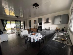 a kitchen and dining room with a table and a kitchen with a sink at Maeva I Papara in Papara