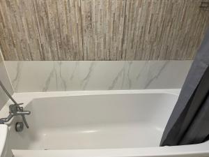 a white bath tub with a shower curtain in a bathroom at Kingsbury Service Accommodation in Colindale