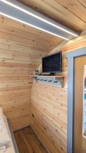a room with wooden walls and a tv in a cabin at Herons Rest Pod By The Sea in Morar Station