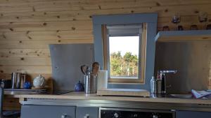 a kitchen with a counter with a window in it at Herons Rest Pod By The Sea in Morar Station +56 photos