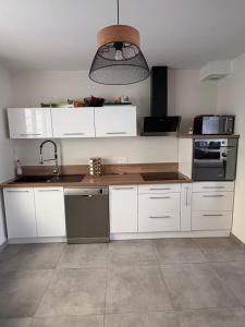 a kitchen with white cabinets and a sink at Maison 2 chambres proche circuit 24h et toutes commodités in Arnage