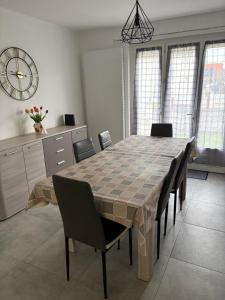 a dining room table with chairs and a clock on the wall at Maison 2 chambres proche circuit 24h et toutes commodités in Arnage