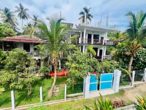 a house with palm trees in front of it at ANB Surf View in Tangalle