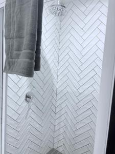 a bathroom with a white tiled shower with a gray towel at Canopy stay 4 in Sandton +3 photos