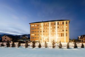 a building in the snow with trees in the foreground at Sentir Hotel in Gura Humorului