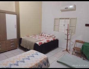 a bedroom with two beds and a dresser and a window at Imperial Hotel in Santo Antônio do Descoberto