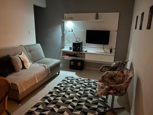a living room with a couch and a tv at Refúgios de Itaúna in Saquarema