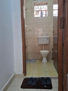 a bathroom with a toilet and a pair of shoes on the floor at MJ Homes Eldoret Studio in Eldoret