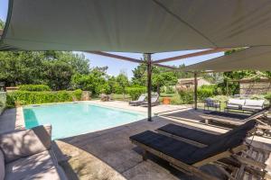 a pool with two lounge chairs and an umbrella at Mas Oréa côté piscine in Gordes +18 photos
