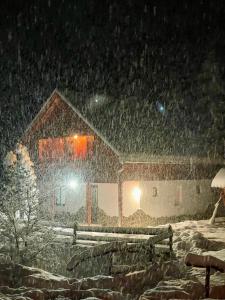 a house is covered in snow at night at Cabana SVA Bilbor in Bilbor