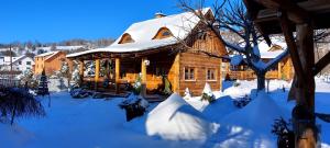 a snow covered log cabin with a snow covered roof at Tylickie Chałupy in Tylicz