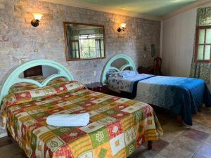 a bedroom with two beds and a stone wall at Hotel Las Flores in Xalapa +43 photos