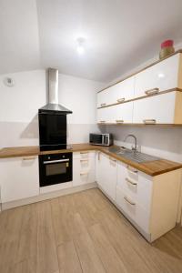 a kitchen with white cabinets and a black stove at Grand studio équipé indépendant in Guipry-Messac