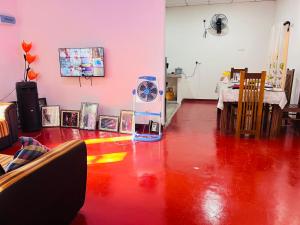 a room with a red floor with a table and a fan at Liyos House in Matara