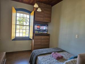 a bedroom with a bed with a tv and a window at Solar das Oliveiras in Ibertioga
