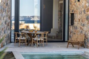 a patio with a table and chairs and a pool at Norte Luxury Villas in Agioi Apostoli