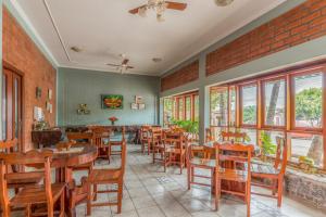un restaurante con mesas y sillas de madera y ventanas en Pousada Rancho Jarinu, en Bonito