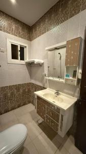 ein Badezimmer mit Waschbecken, Toilette und Spiegel in der Unterkunft فواصل2 in Tabuk + 2 Fotos