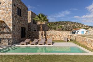 a villa with a swimming pool and lounge chairs at Norte Luxury Villas in Agioi Apostoli