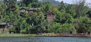 a group of houses on a hill next to the water at Mutanda Eco Community Center in Kisoro +61 photos