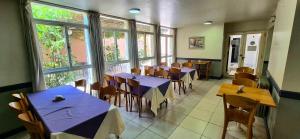 ein Restaurant mit blauen Tischen, Stühlen und Fenstern in der Unterkunft Hotel Puerta del Sol in Mendoza