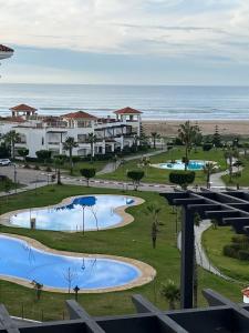 a view of the beach from the balcony of a resort at Beachfront Apartment in Assilah, Private Solarium, 4 Pools, Secure Residence, WiFi, Parking in Asilah