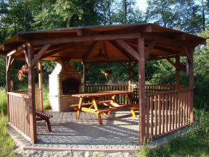 a wooden gazebo with a wooden table and bench at Domki drewniane alpejskie in Świętne