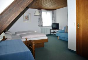 a bedroom with a bed and a couch and a tv at Pension Deifel in Daisendorf