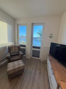 a living room with a couch and a tv and two windows at Seglerblick in Greifswald
