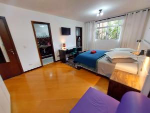 a bedroom with a bed and a desk and a mirror at Pousada Casa Verde - Curitiba in Curitiba